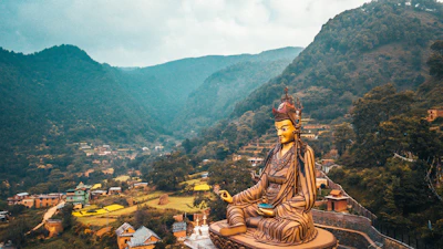 woman in yellow and brown dress sitting on brown concrete bench during daytime