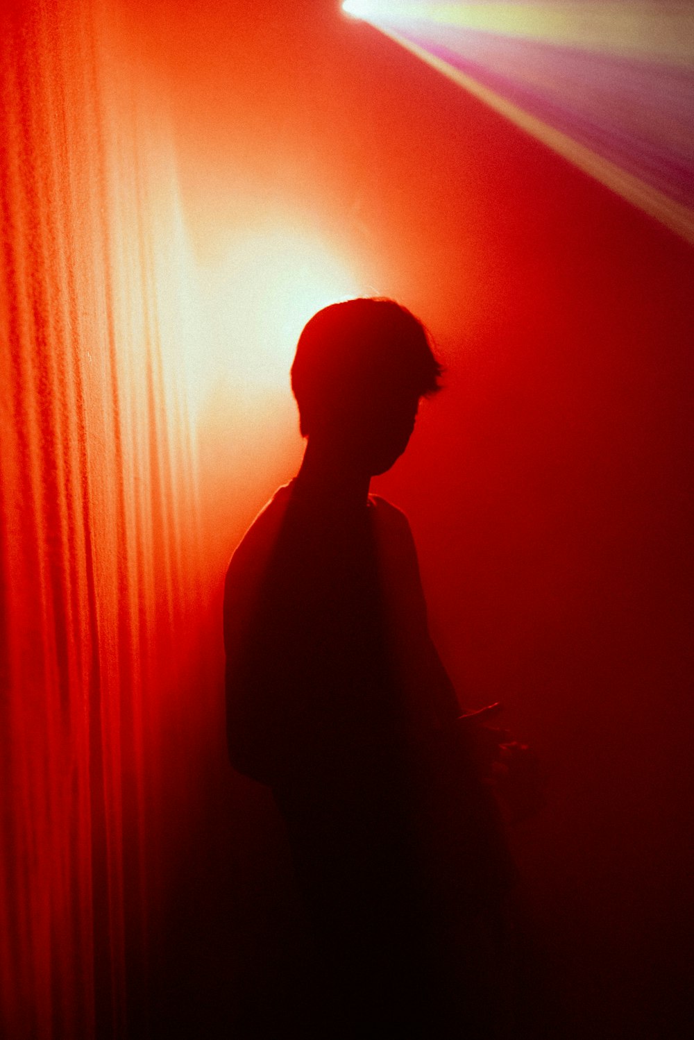 silhouette of man standing near red curtain