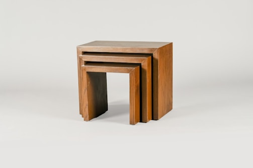 A set of wooden nesting tables with smooth grain and a small terracotta planter on top.