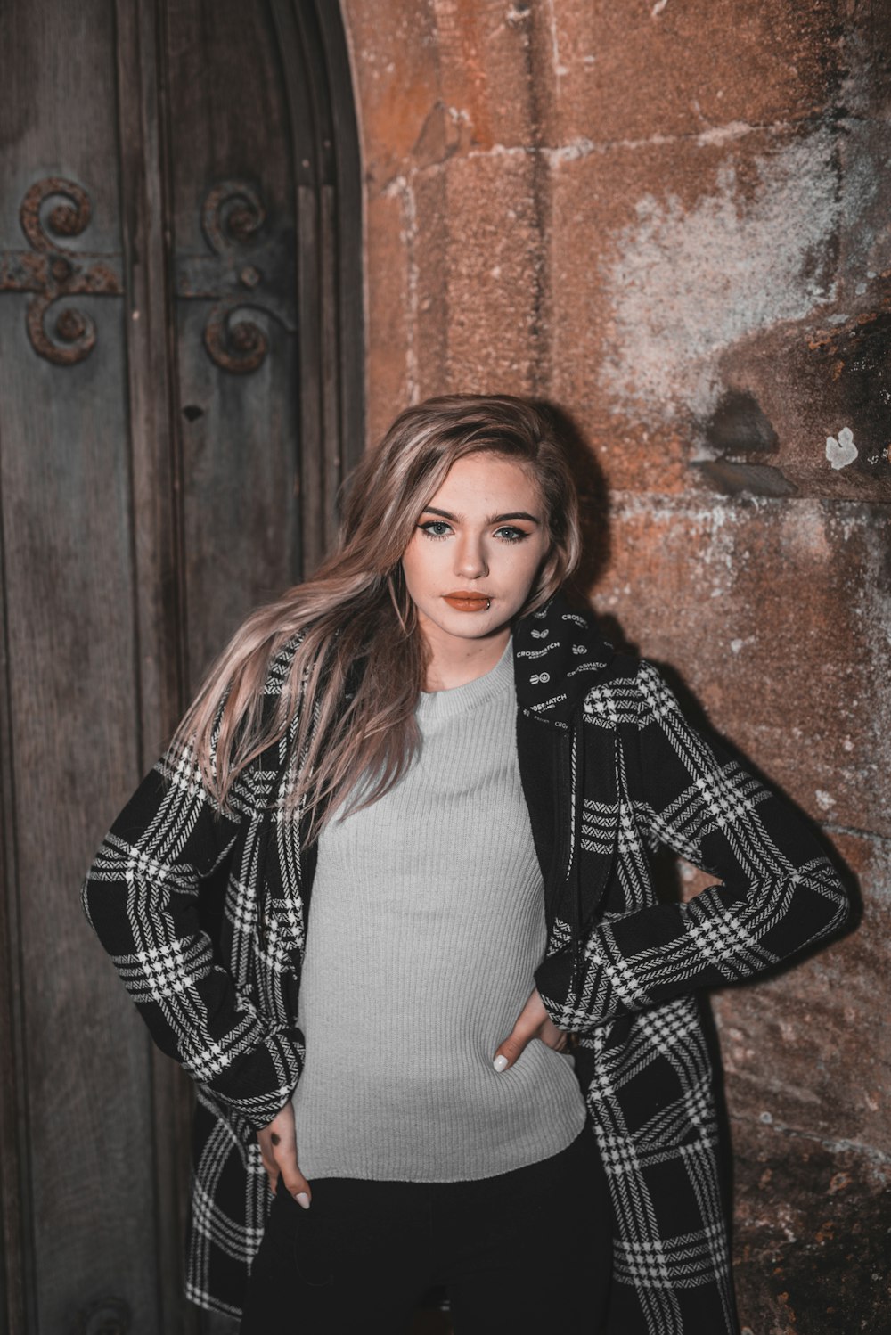 woman in black and white checkered blazer standing beside brown brick wall