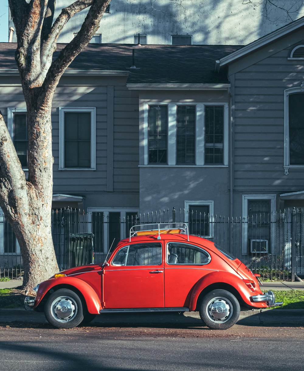 red volkswagen beetle parked beside brown concrete building during daytime