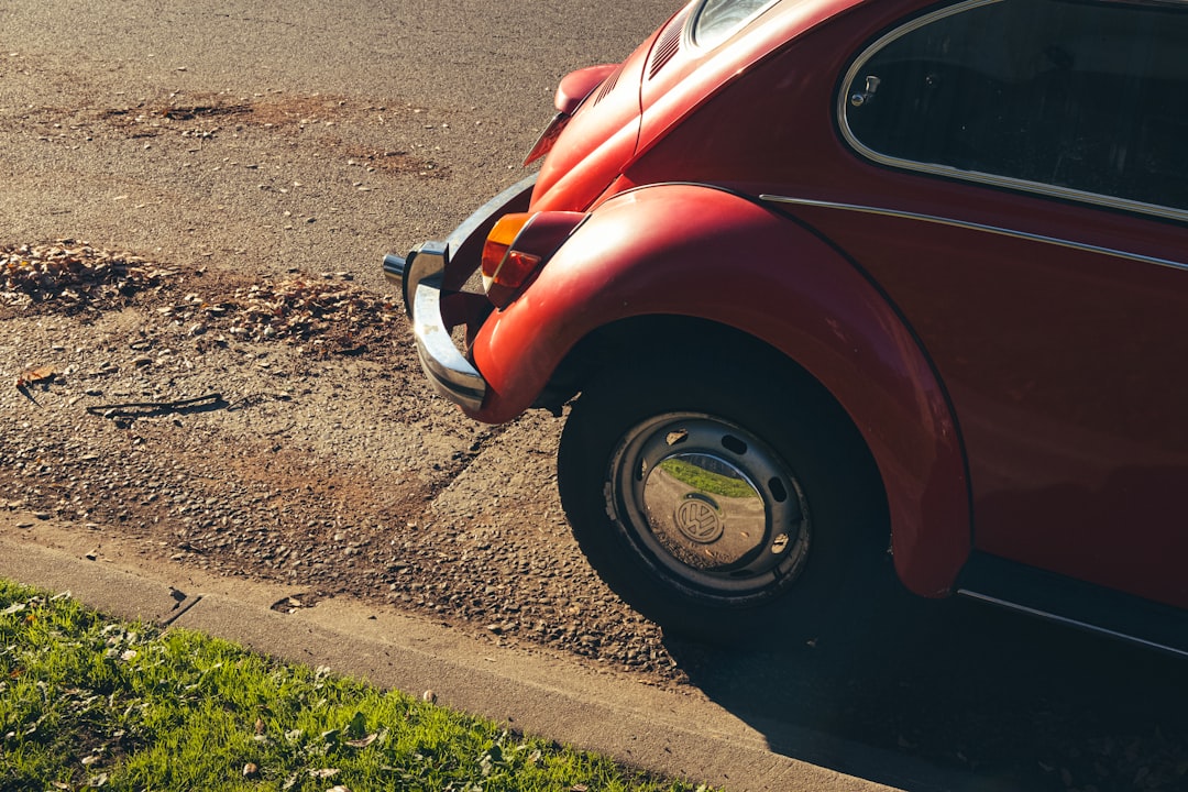 red and white volkswagen beetle parked on the side of the road