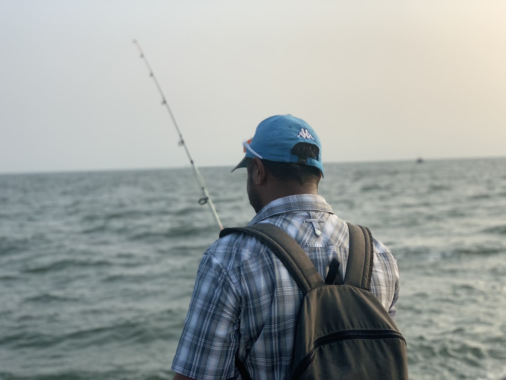 Hombre con gorra azul y camisa a cuadros pescando durante el día