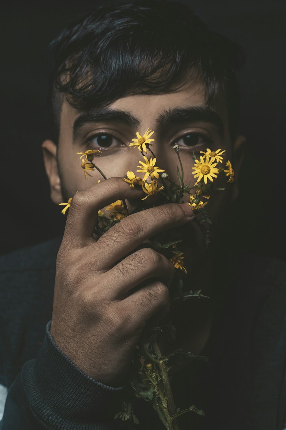 man in blue crew neck shirt holding yellow flower