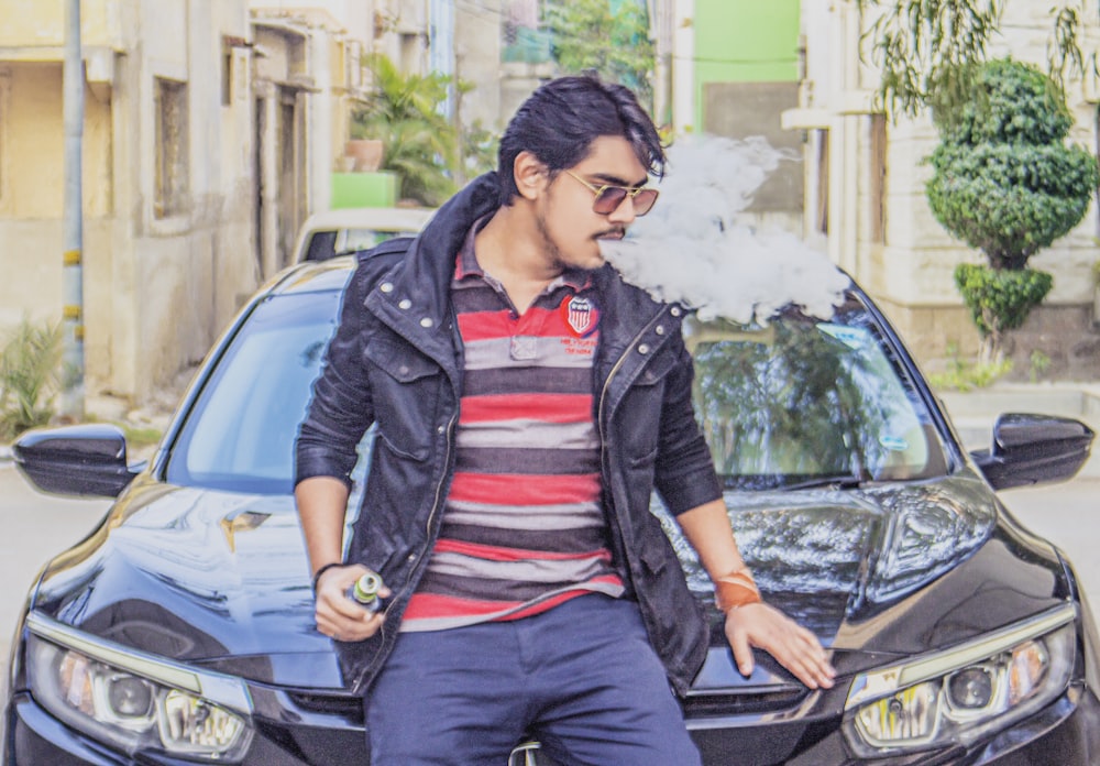 man in black leather jacket sitting on black car