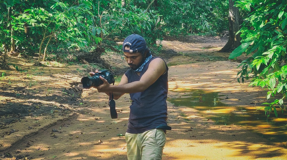 man in black tank top and brown shorts holding black dslr camera