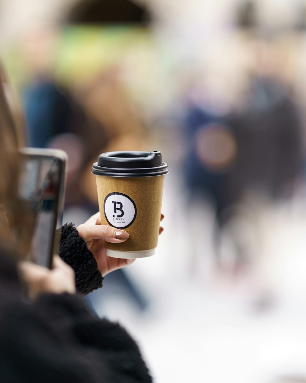 person holding brown and black coffee cup