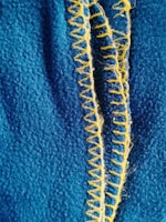 A close-up of detailed stitching on a yellow sofa fabric.