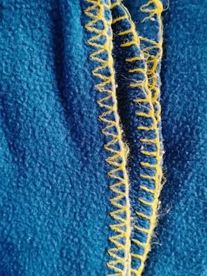 Close-up of the intricate stitching detail on the yellow sundress fabric.