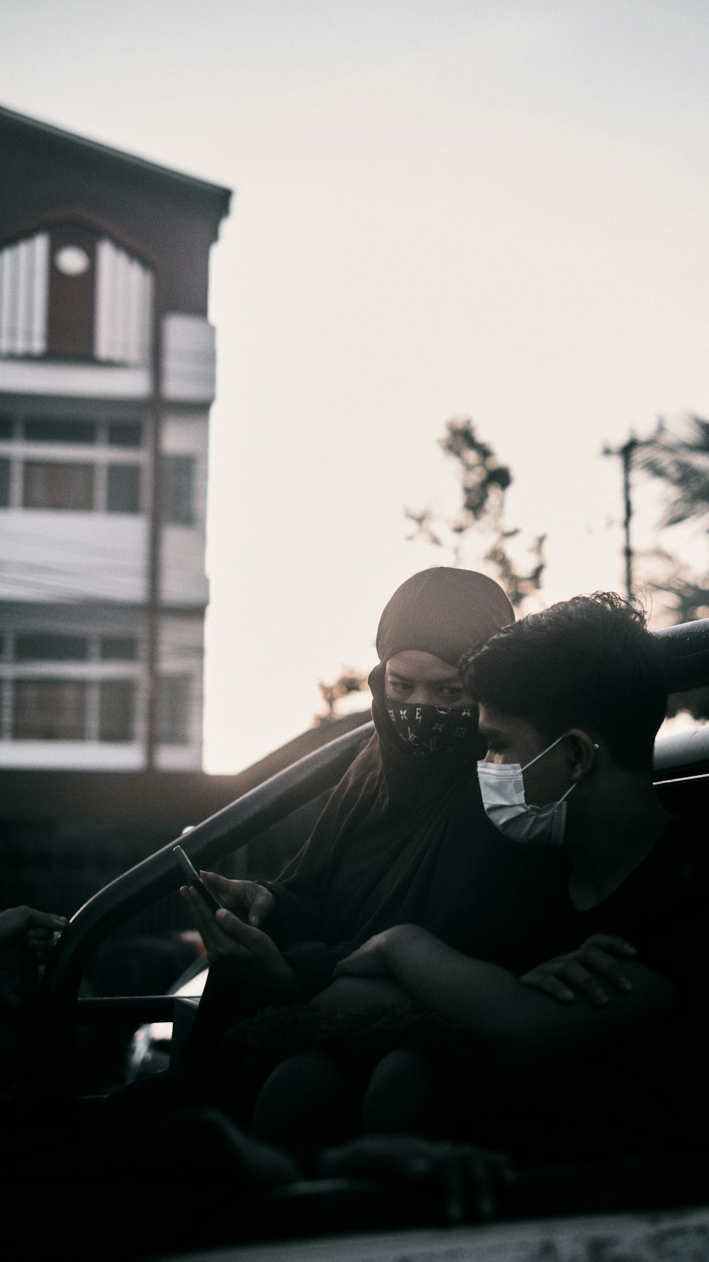 man in black crew neck t-shirt sitting on black car during daytime