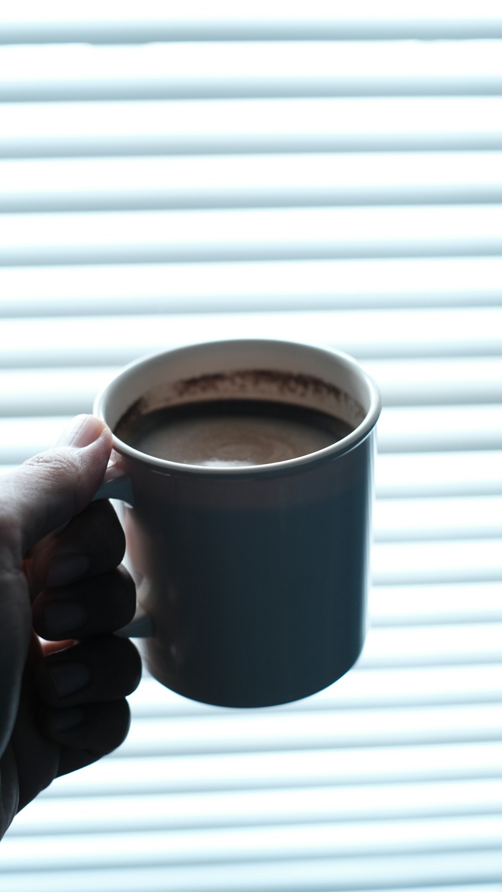person holding black ceramic mug with brown liquid