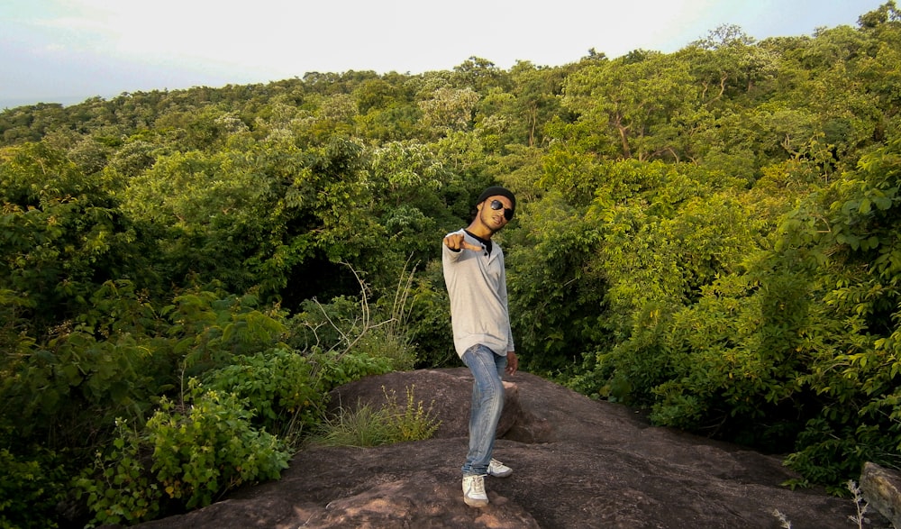 woman in white shirt and blue denim jeans standing on dirt road during daytime