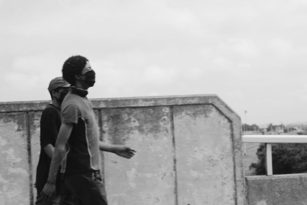 man in black t-shirt and black pants standing beside concrete wall during daytime