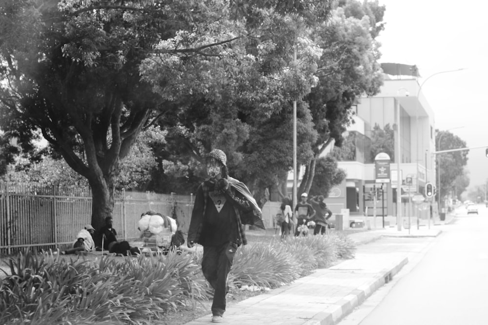 grayscale photo of man and woman walking on sidewalk