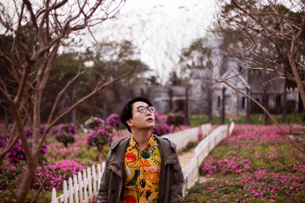 woman in black jacket standing near pink flowers and trees during daytime