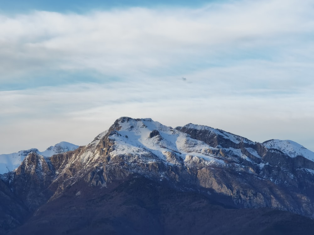 montanha coberta de neve sob céu nublado durante o dia