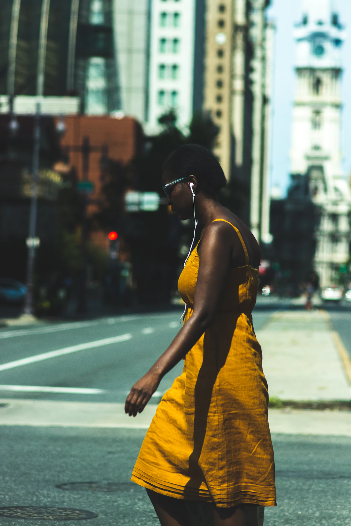 Woman in summer outfit walking down a city sidewalk on a hot day