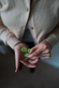 person in white blazer holding green heart ornament