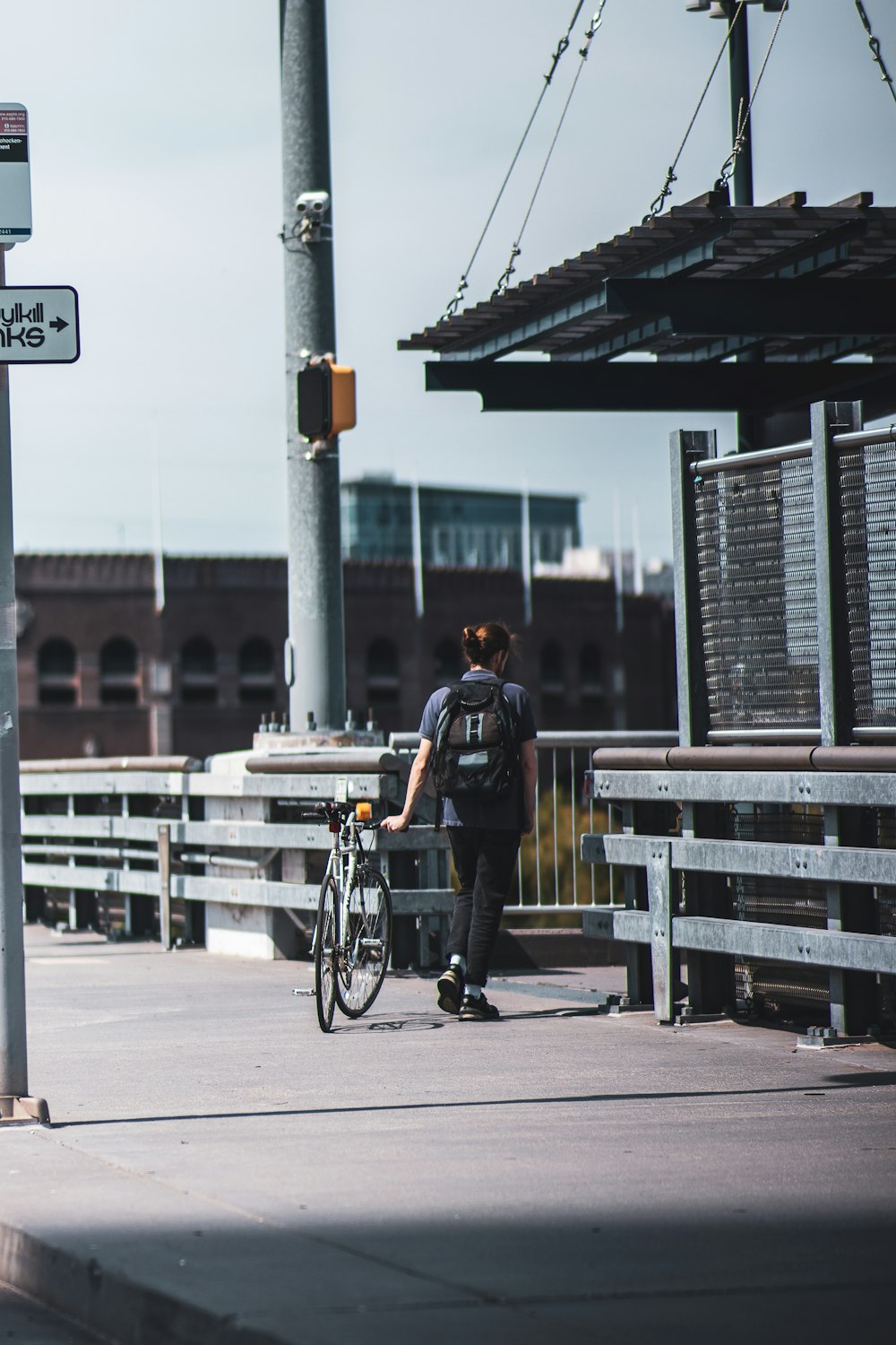 man in black jacket and blue denim jeans riding bicycle on road during daytime