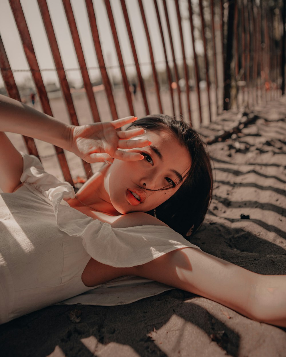 woman in white dress lying on sand during daytime