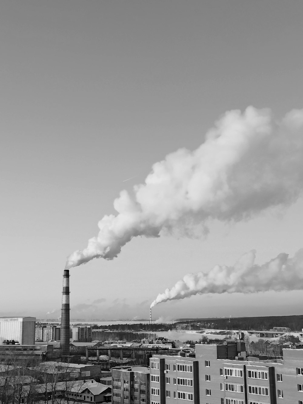 grayscale photo of factory under cloudy sky