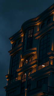 Elegant residential building with warm lighting at dusk, showcasing architectural details.