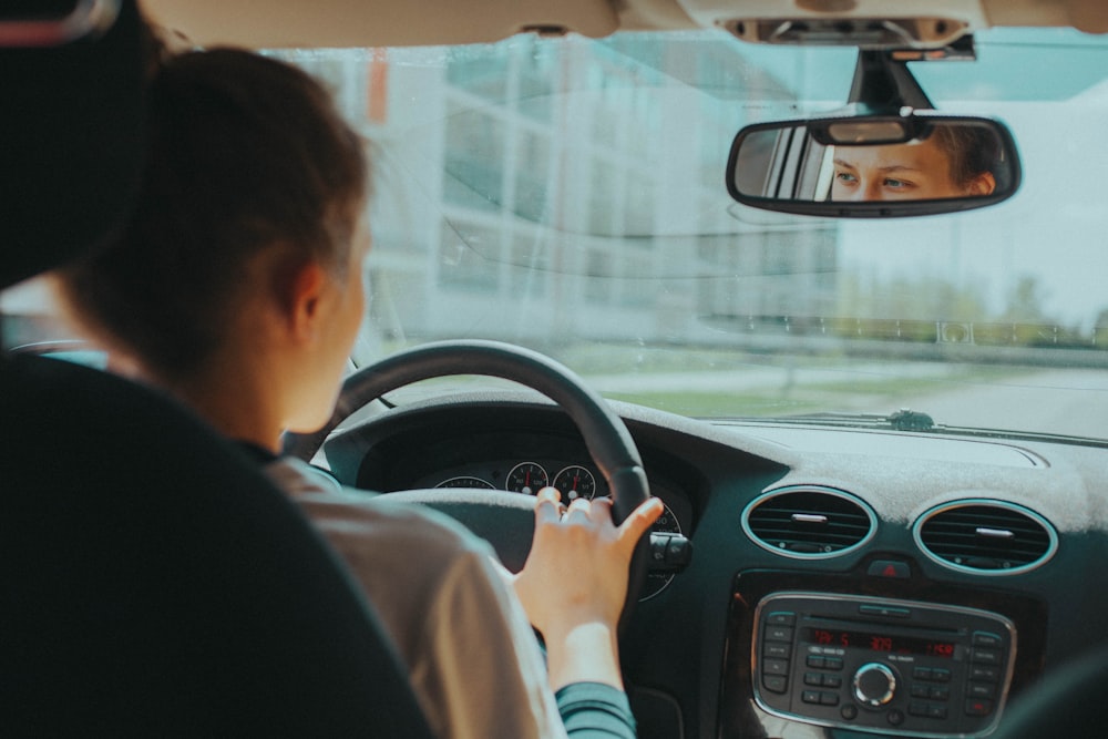 uomo in camicia nera che guida l'auto