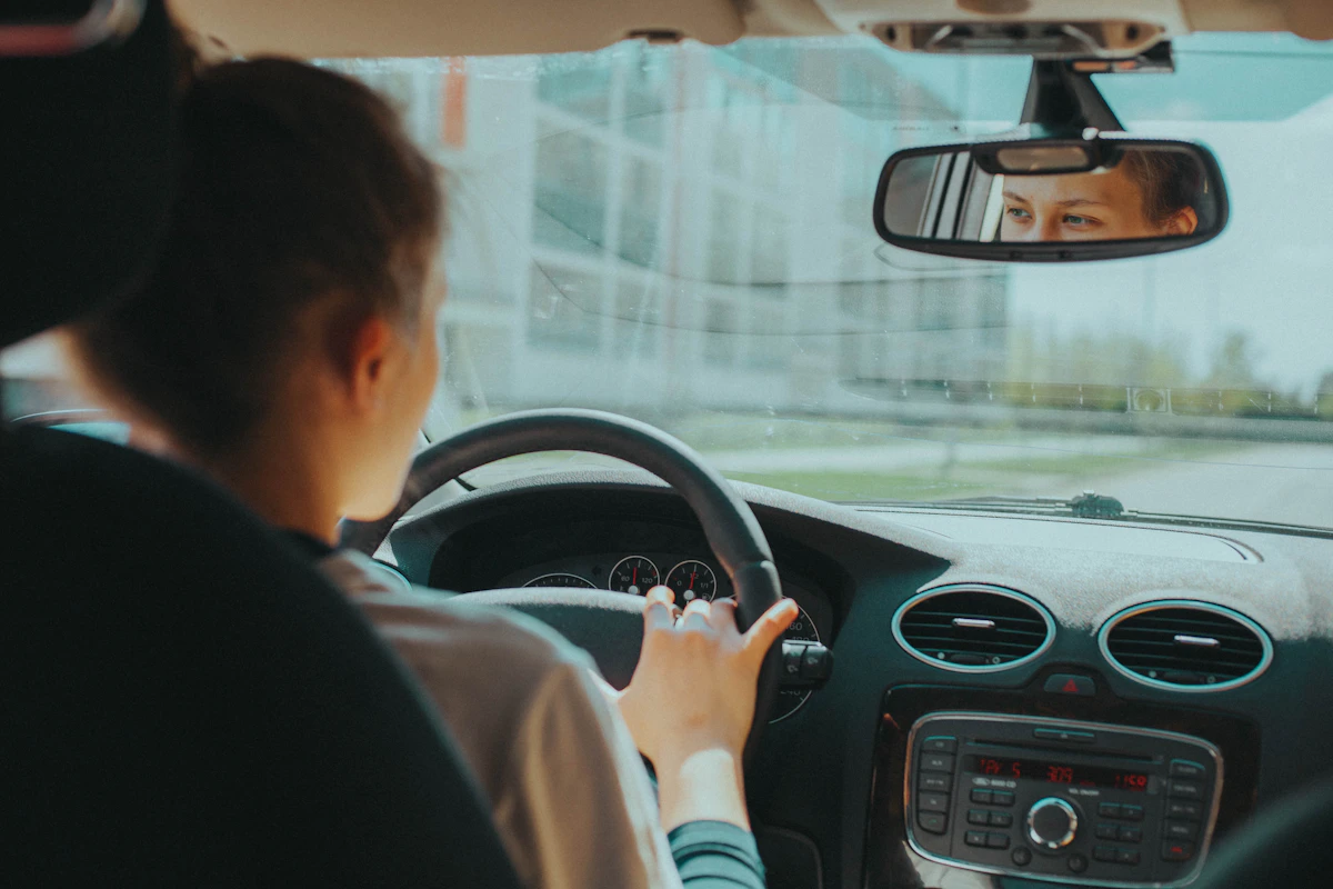 Rijles in de auto, de instructeur kijkt mee via de spiegel