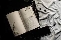 An open book with handwritten poems resting beside vintage headphones.