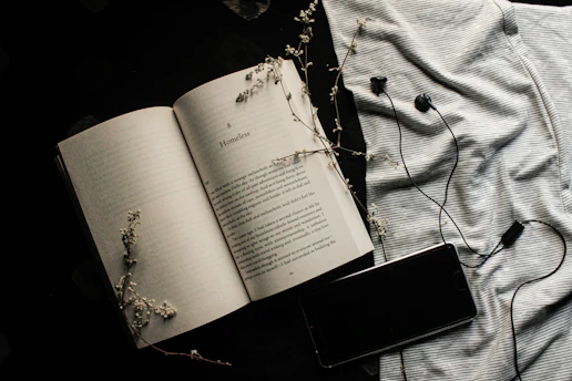 An open book beside headphones resting on a wooden table, inviting to listen.
