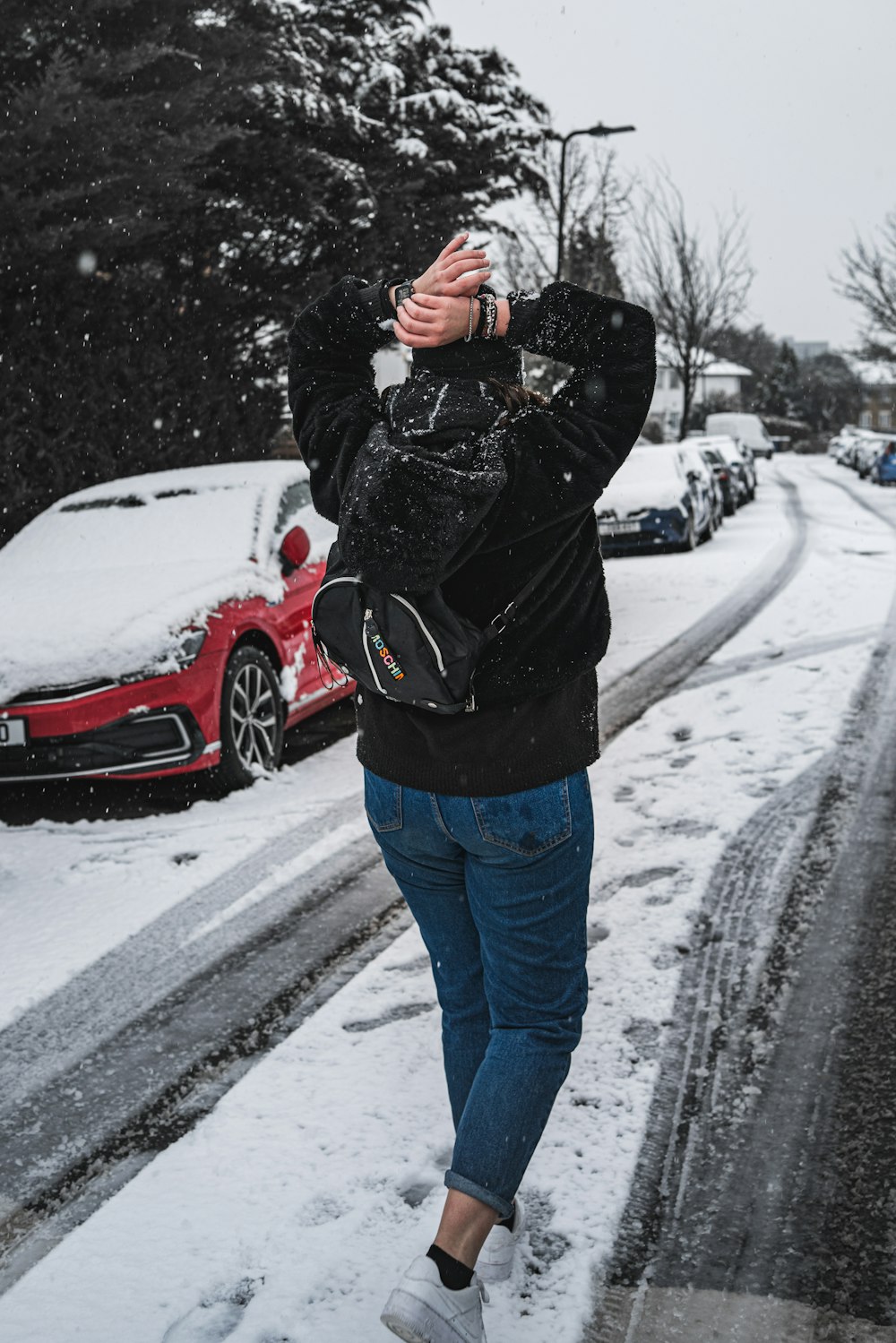 man in black jacket and blue denim jeans standing on snow covered road during daytime