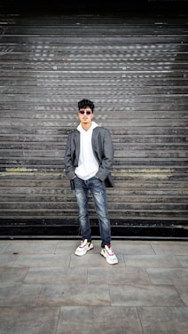 A stylish model wearing a pgf clothing hoodie and jean suit, standing against a vibrant Harlem street mural.