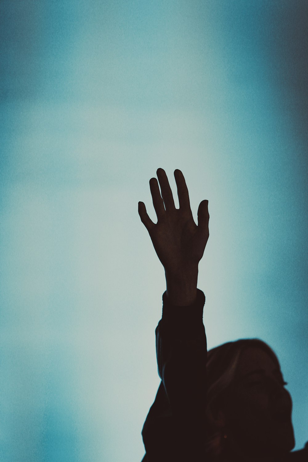 silhouette of man raising his right hand