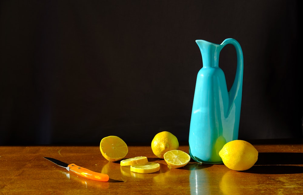 blue pitcher beside sliced lemon on brown wooden table