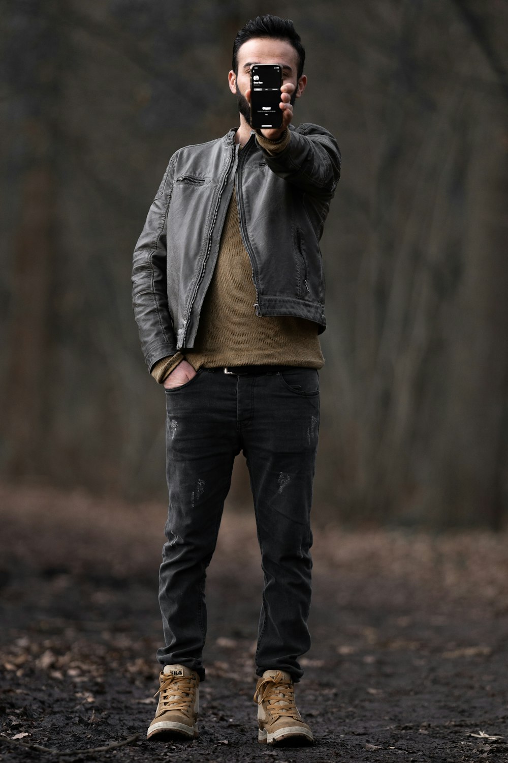 uomo in giacca grigia e jeans blu in denim in piedi sul campo marrone durante il giorno