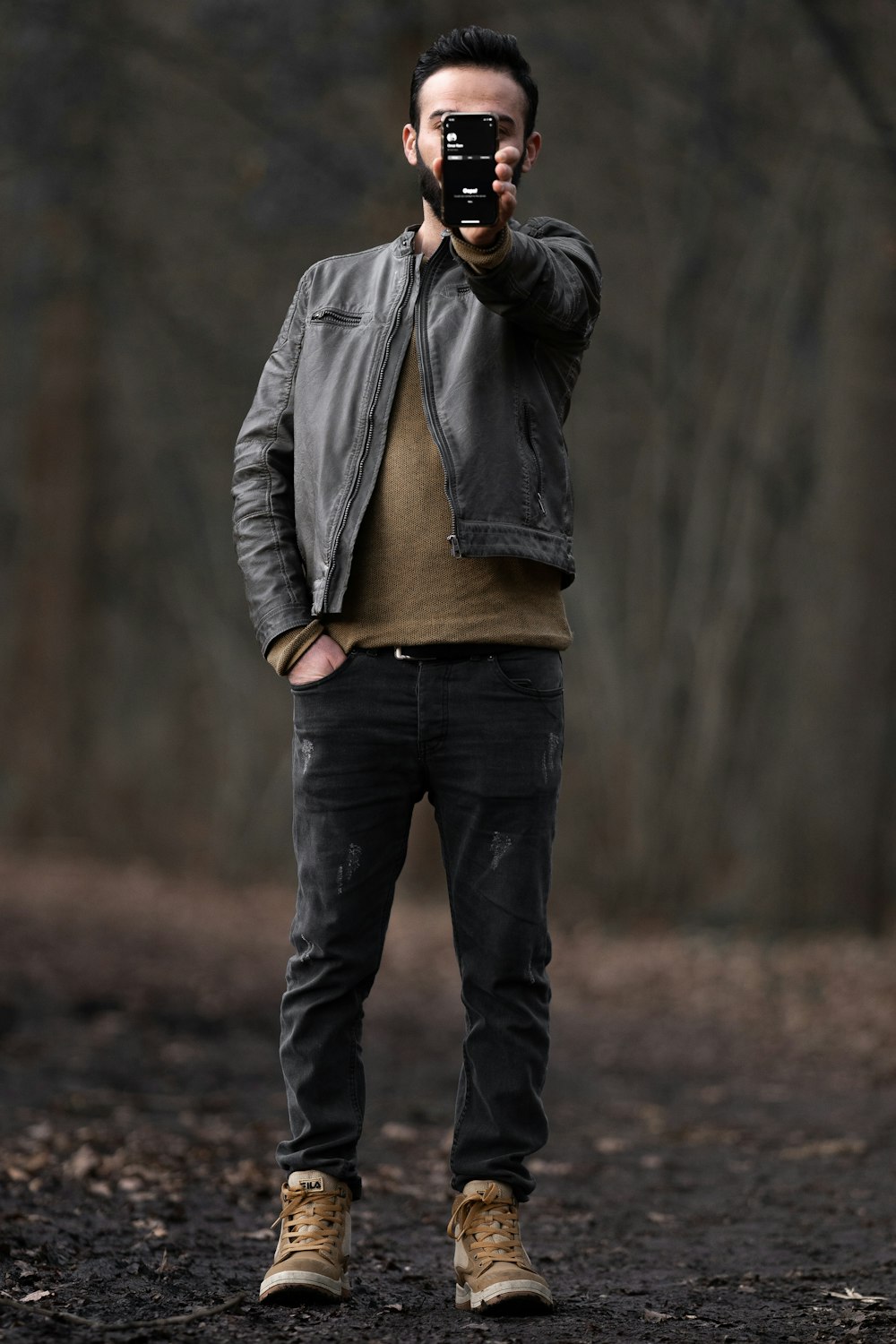 man in gray jacket and blue denim jeans standing on brown field during daytime