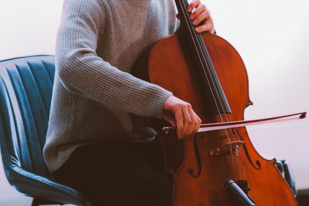 man in gray sweater playing brown violin