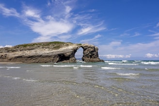 brown rock formation on sea under blue sky during daytime