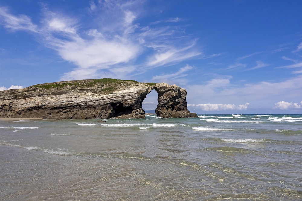 brown rock formation on sea under blue sky during daytime