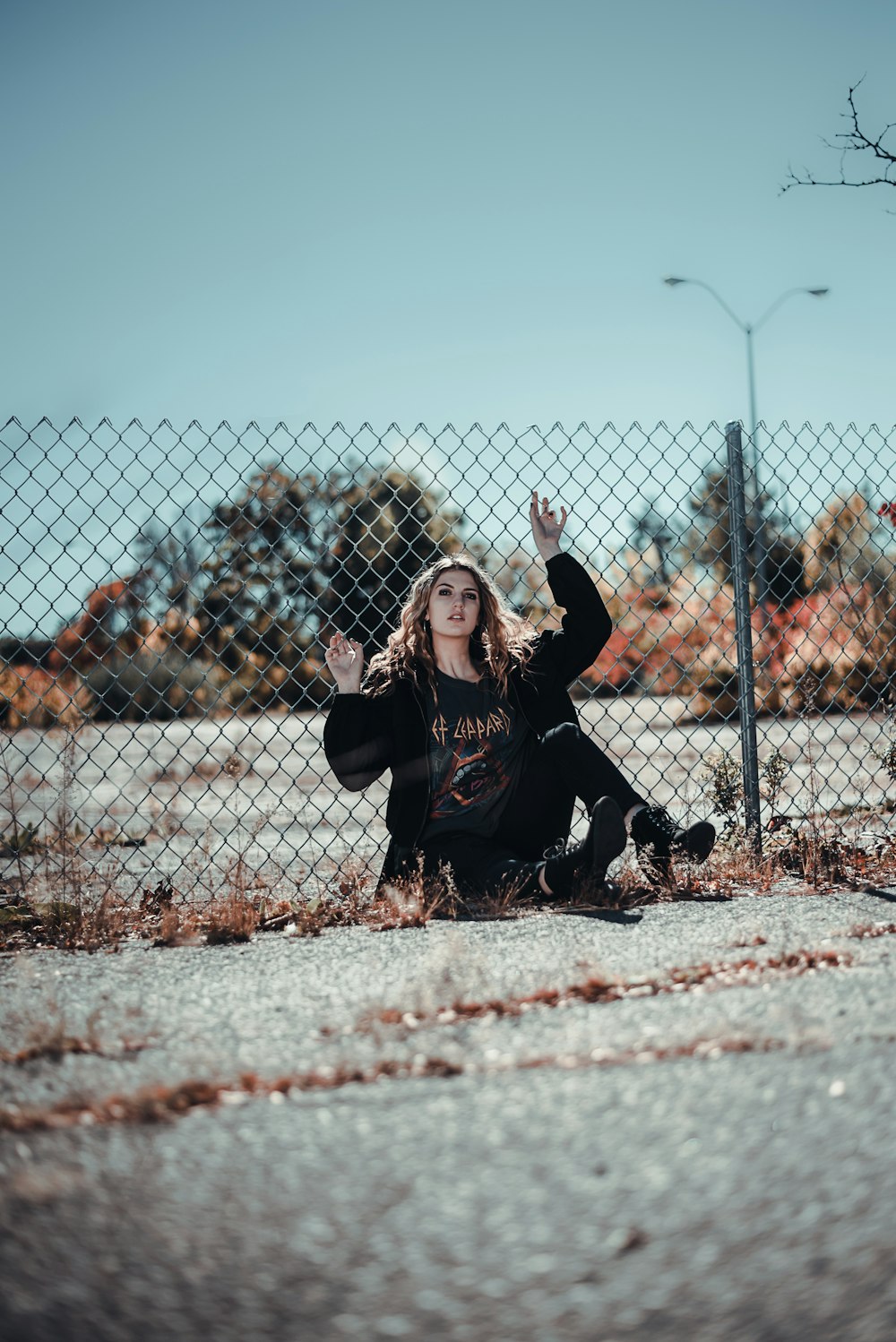 woman in black jacket and black pants sitting on brown dried leaves during daytime