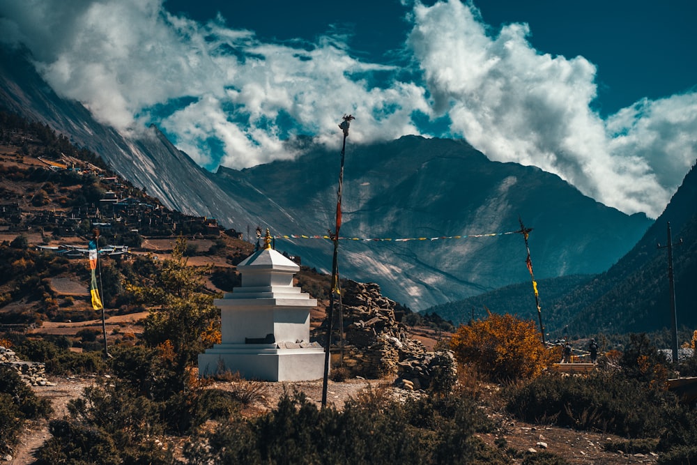 white and brown concrete building near mountain under white clouds and blue sky during daytime