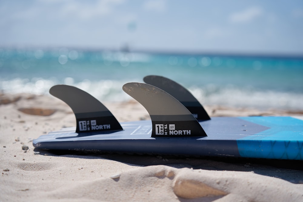 昼間の白い砂浜の青いサーフボード