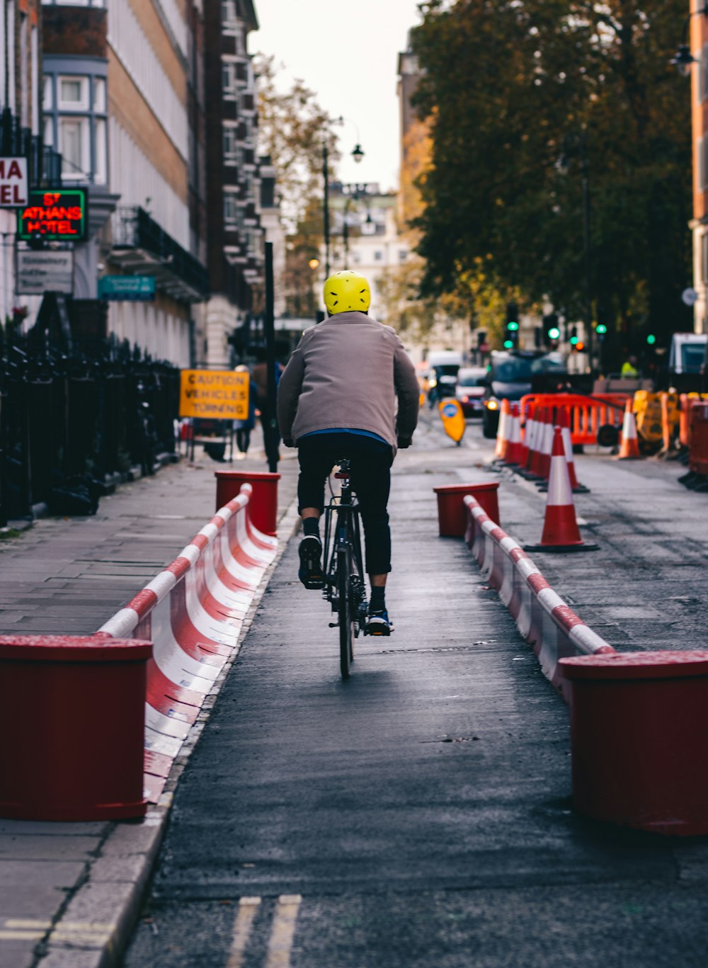 Mann in schwarzer Jacke fährt tagsüber Fahrrad auf der Straße