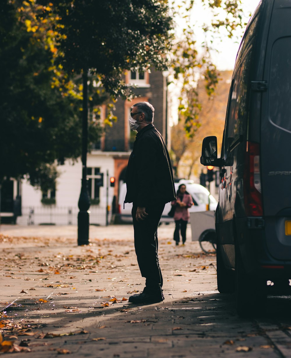 man in black jacket walking on sidewalk during daytime