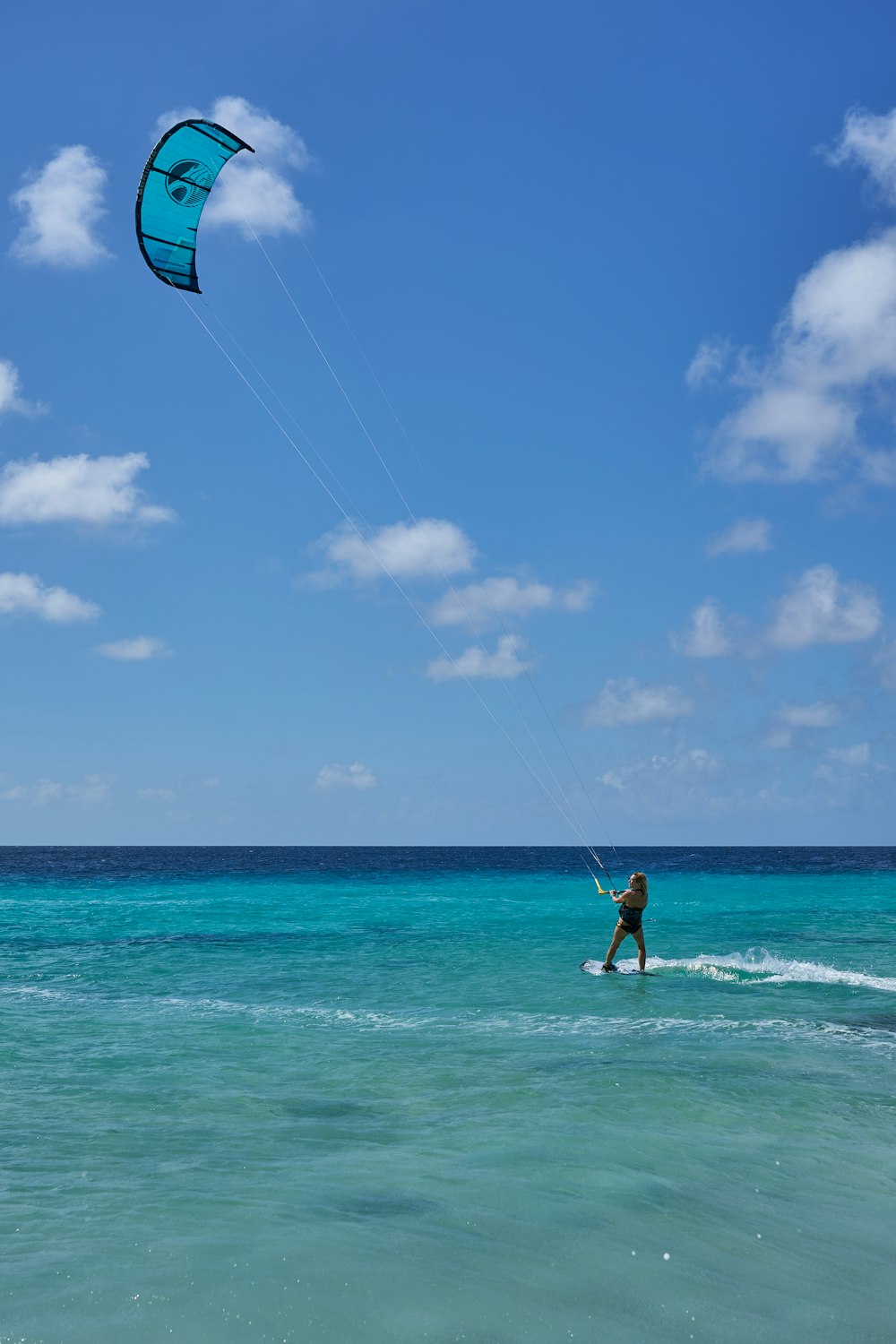 Frau im weißen und schwarzen Bikini mit blau-weißem Kitesurfen auf See tagsüber