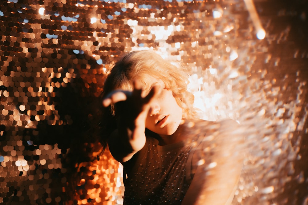 woman in brown shirt with white string lights on her face