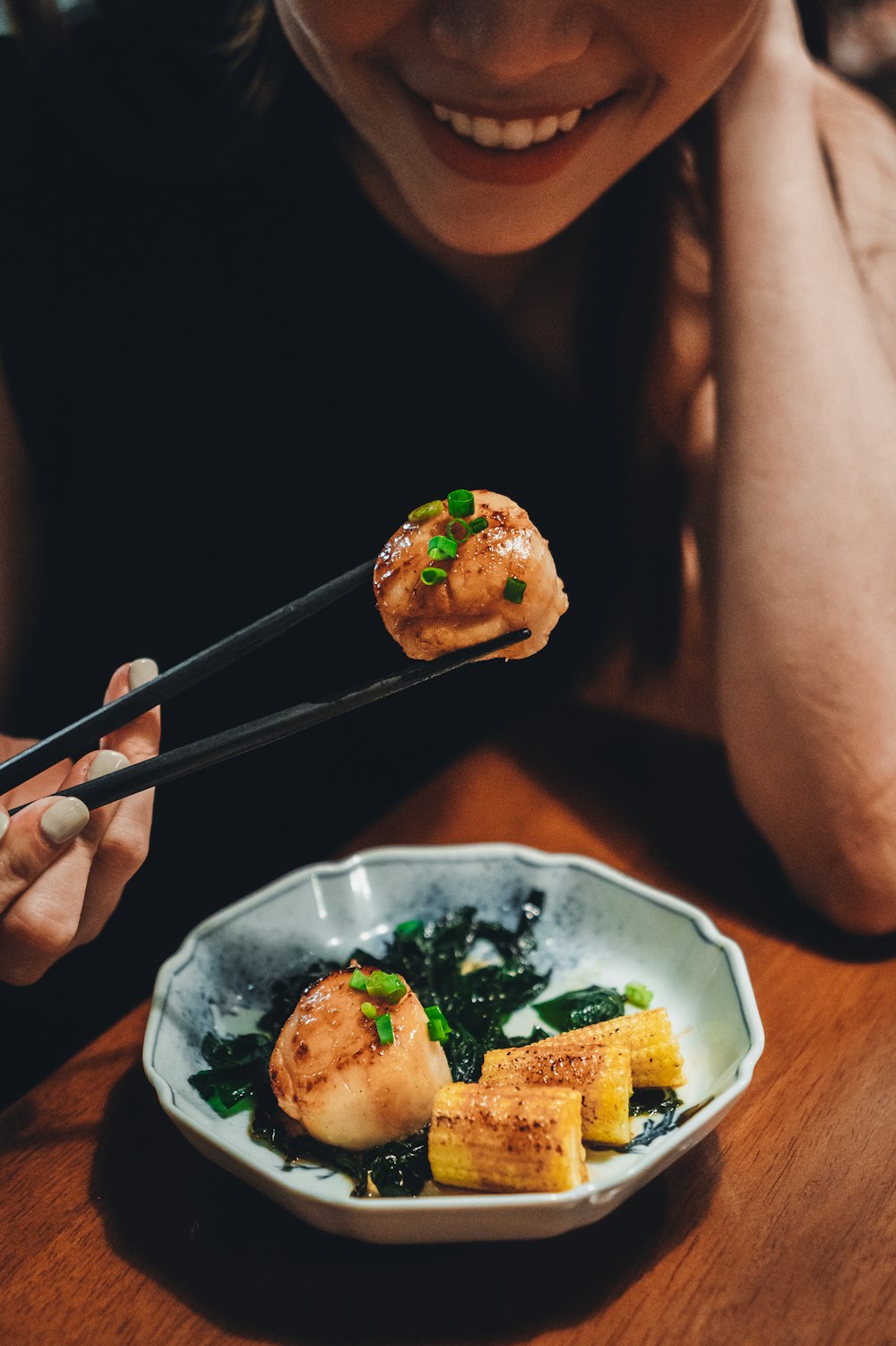 person holding chopsticks with food on white ceramic plate