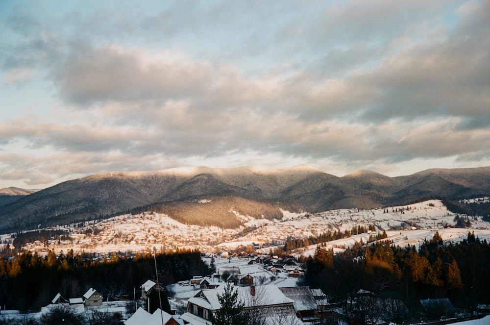 white and brown houses near brown mountains under white clouds during daytime