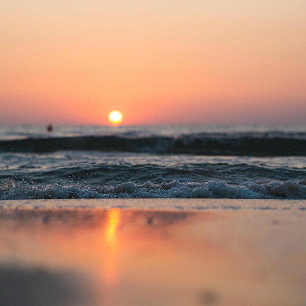 sea waves crashing on shore during sunset