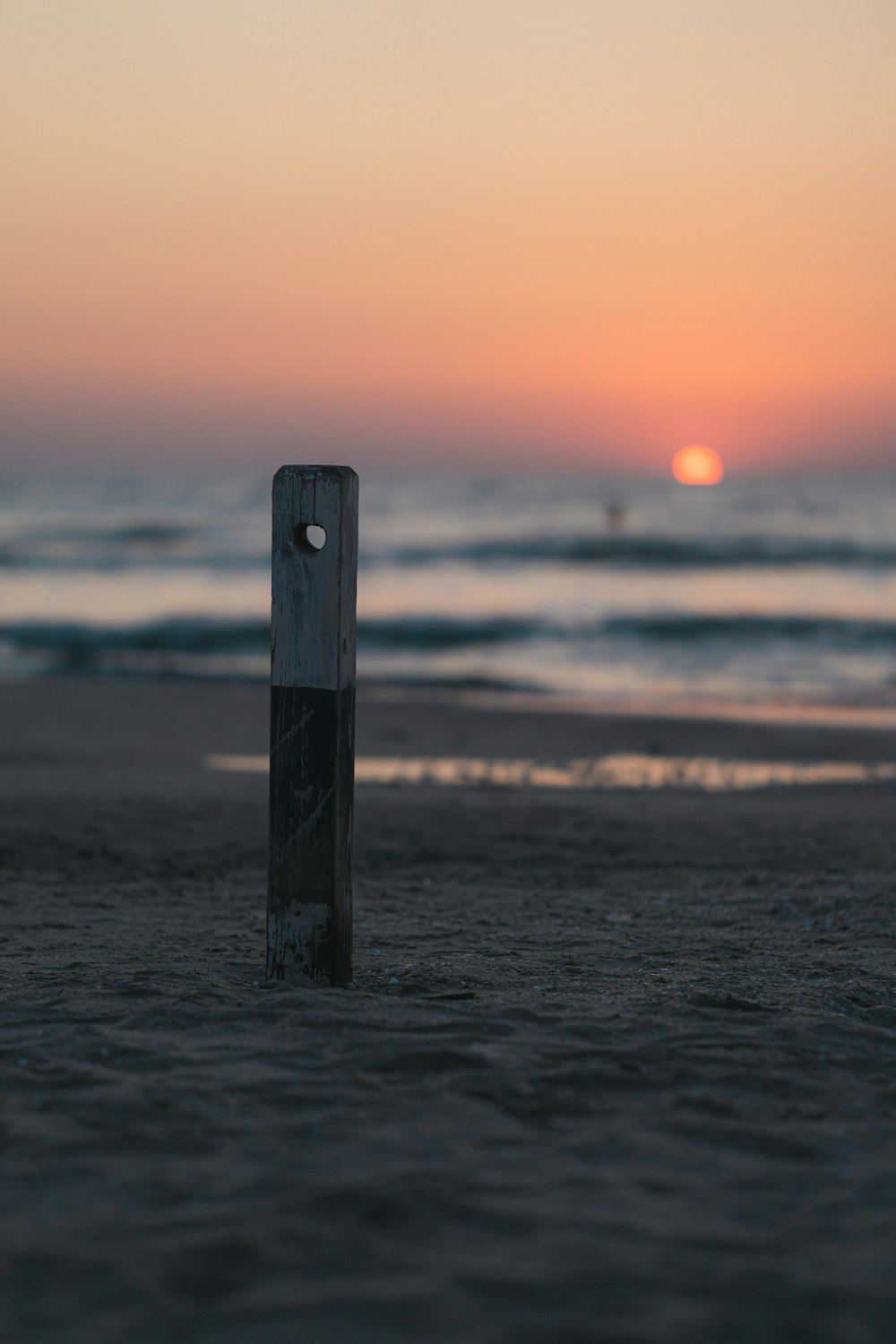 brown wooden post on sea during sunset